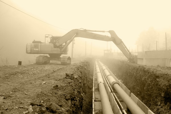 Excavator beside large sewer pipes at construction site